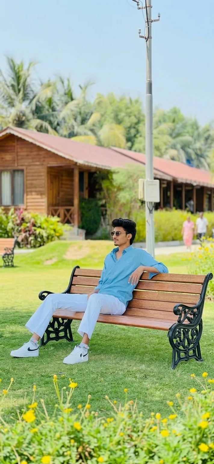 Candid Outdoor Portrait of Young Man Relaxing on Wooden Park Bench
